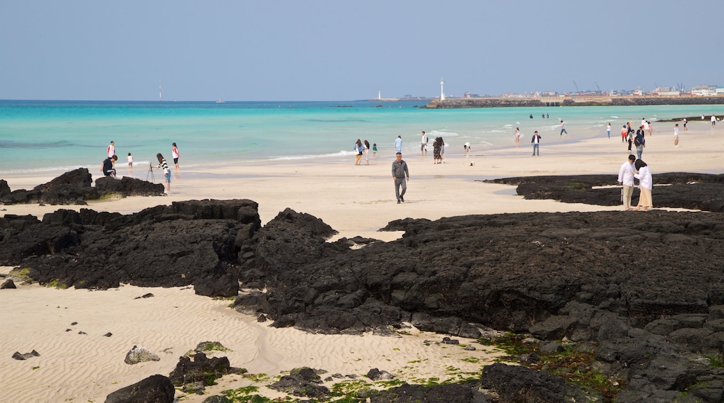 Hyeopjae Beach which includes a beach and general coastal views as well as a small group of people