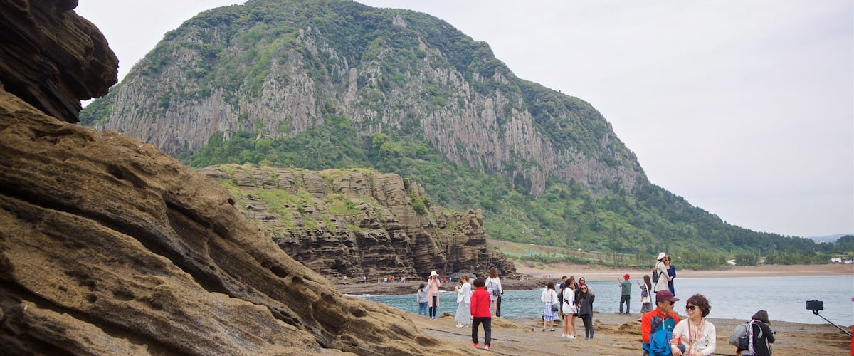 Yongmeori Coast featuring rocky coastline and general coastal views as well as a small group of people