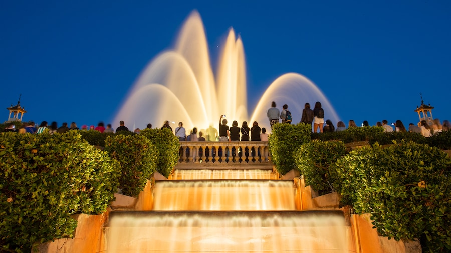 Evening view of the Magic Fountain of Montjuïc in Barcelona, with illuminated water jets and a crowd gathered to enjoy the light and music show.