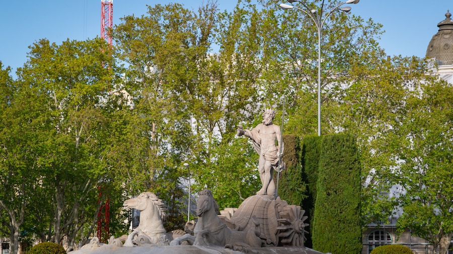 Fountain of Neptune featuring a statue or sculpture and a garden