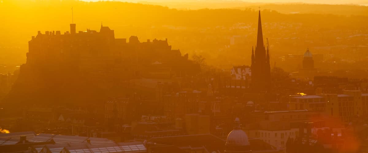 Arthur\'s Seat que inclui um castelo, um pôr do sol e uma cidade