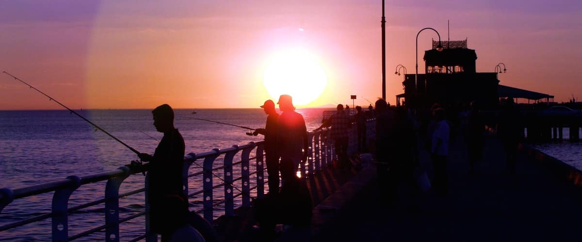 St. Kilda Beach which includes a sunset, fishing and a coastal town