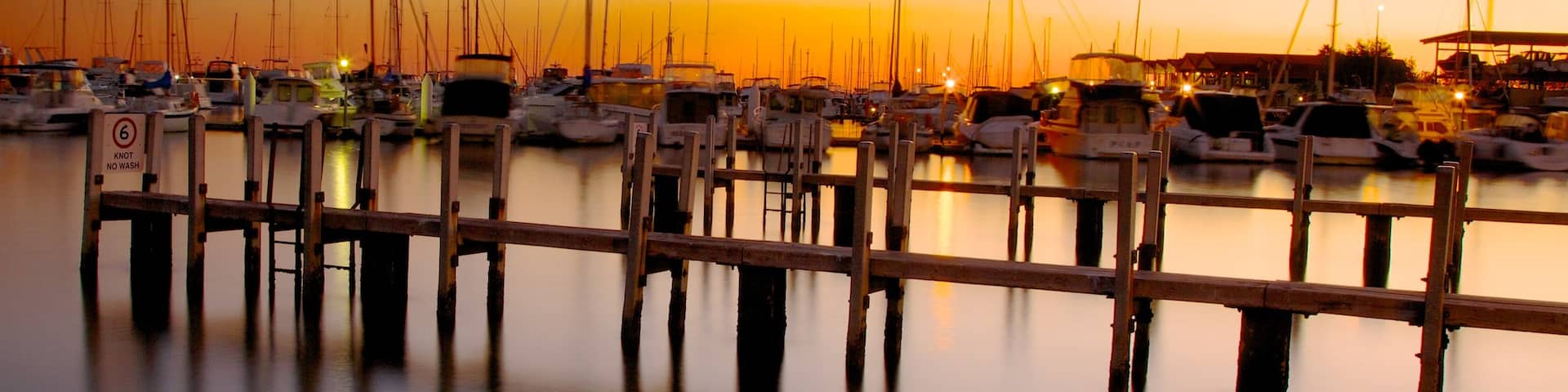 Hillarys Boat Harbour showing a coastal town, a sunset and a bay or harbor
