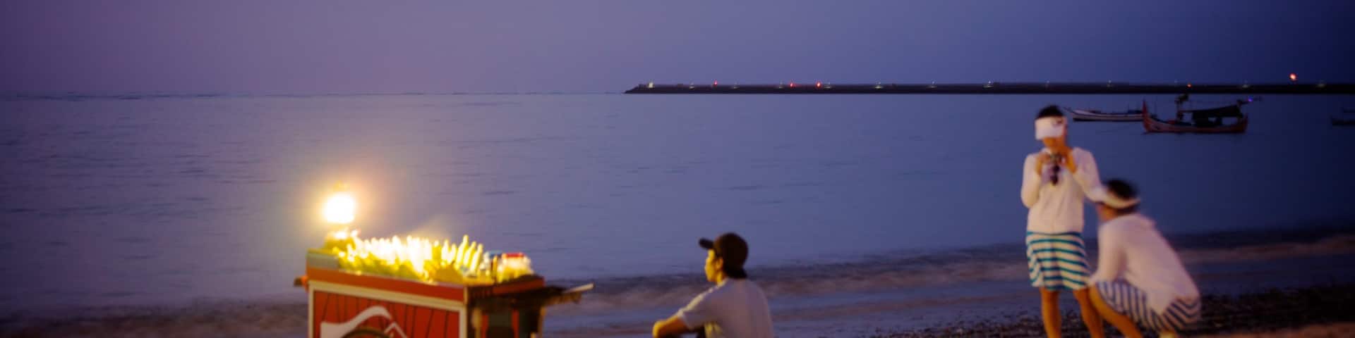 Jimbaran Beach featuring night scenes and a sandy beach as well as a small group of people