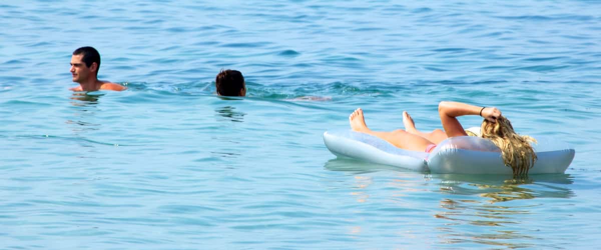 Segara Beach featuring swimming and waves as well as a small group of people