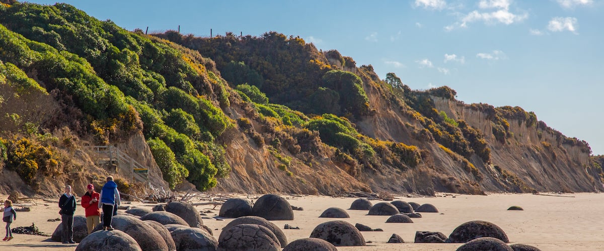 Moeraki Boulders which includes a beach as well as a small group of people