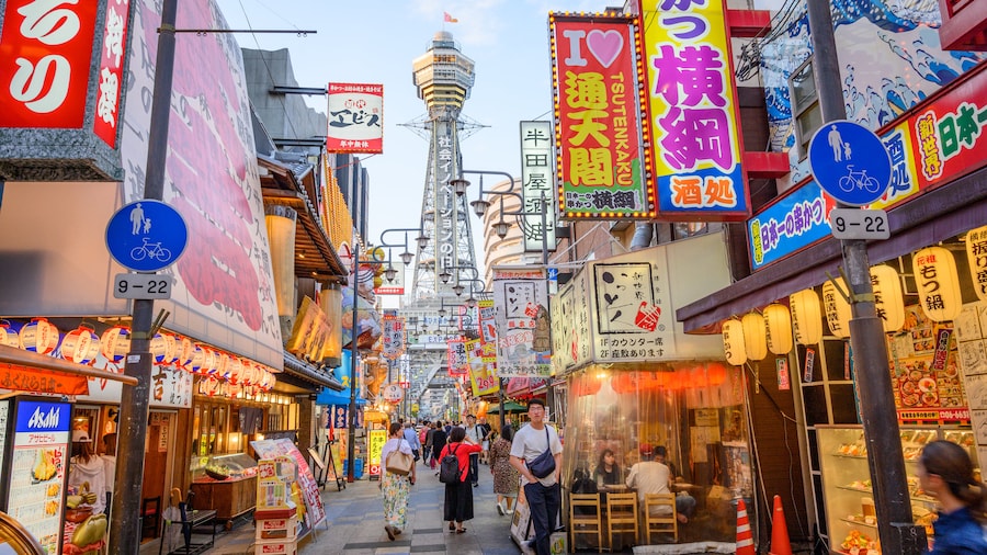 Tsutenkaku Tower with vibrant street scenes in Shinsekai district, Osaka, Japan.