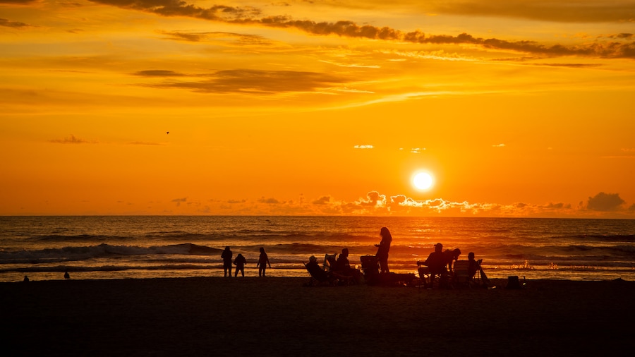 Seaside featuring a sunset and general coastal views as well as a small group of people