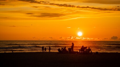 Seaside featuring a sunset and general coastal views as well as a small group of people