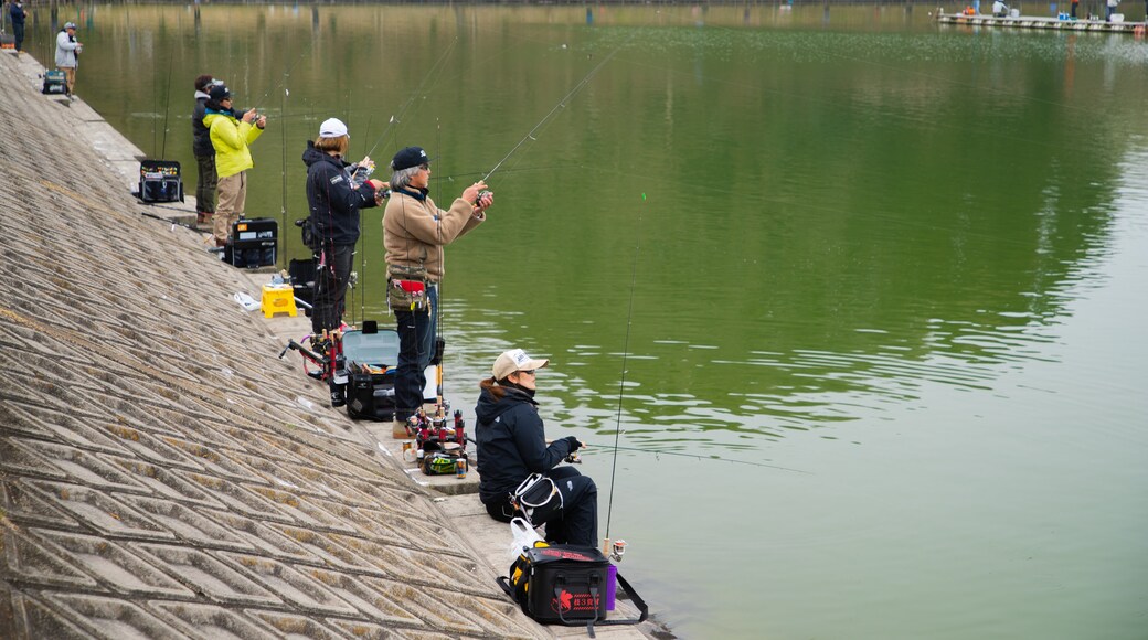 Lake Higashiyama featuring fishing and a lake or waterhole as well as a small group of people