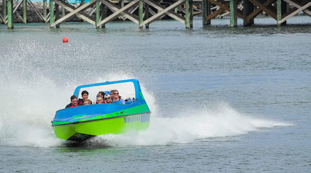 Broadway at the Beach featuring boating and a lake or waterhole as well as a small group of people