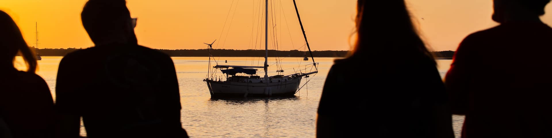 Downtown Dunedin showing a sunset and boating as well as a small group of people