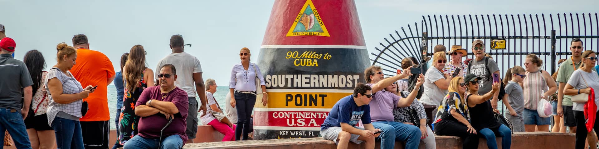 Southernmost Point featuring signage as well as a large group of people