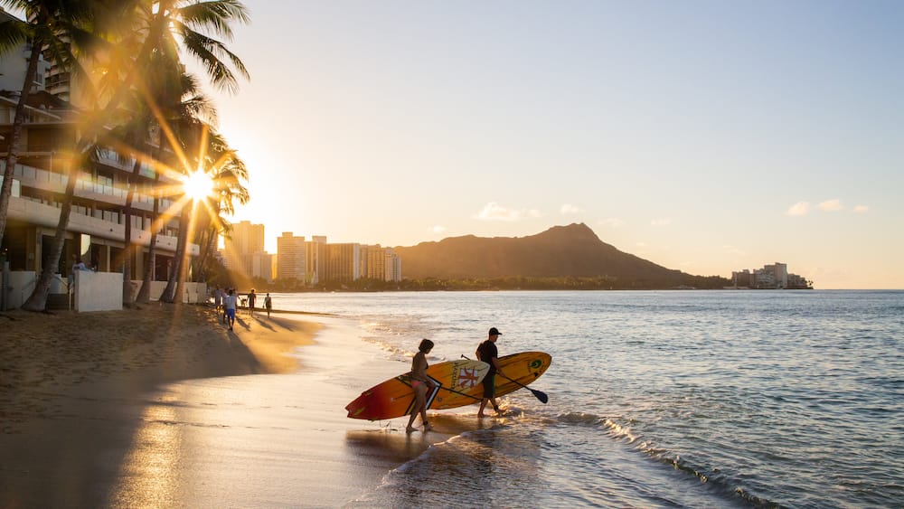 Waikiki Beach featuring a coastal town, kayaking or canoeing and a sunset