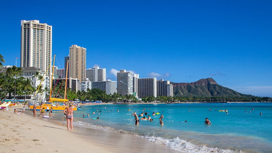 Tourists enjoying Waikiki Beach with Diamond Head in the background.