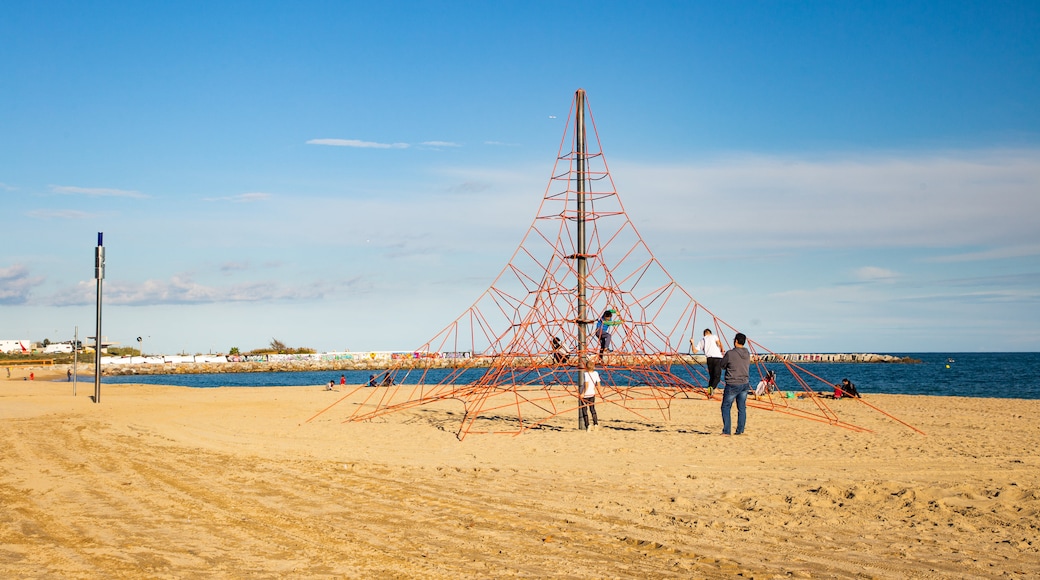 Mar Bella Beach featuring a playground and a sandy beach as well as a family