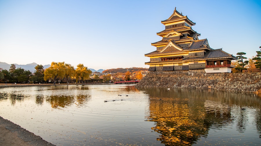Matsumoto Castle featuring a pond, heritage architecture and a sunset