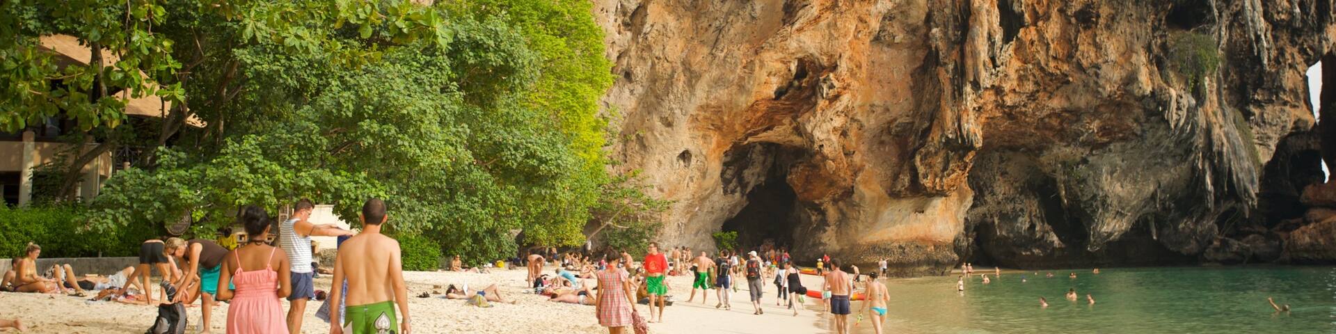 West Railay Beach showing a sandy beach and a gorge or canyon as well as a large group of people
