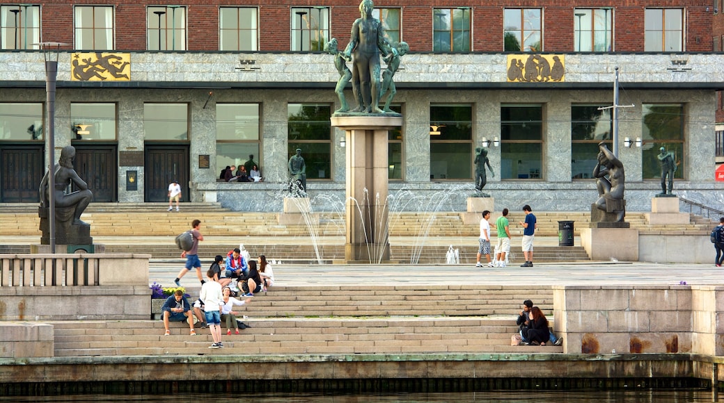 Aker Brygge que incluye una plaza, una fuente y una estatua o escultura