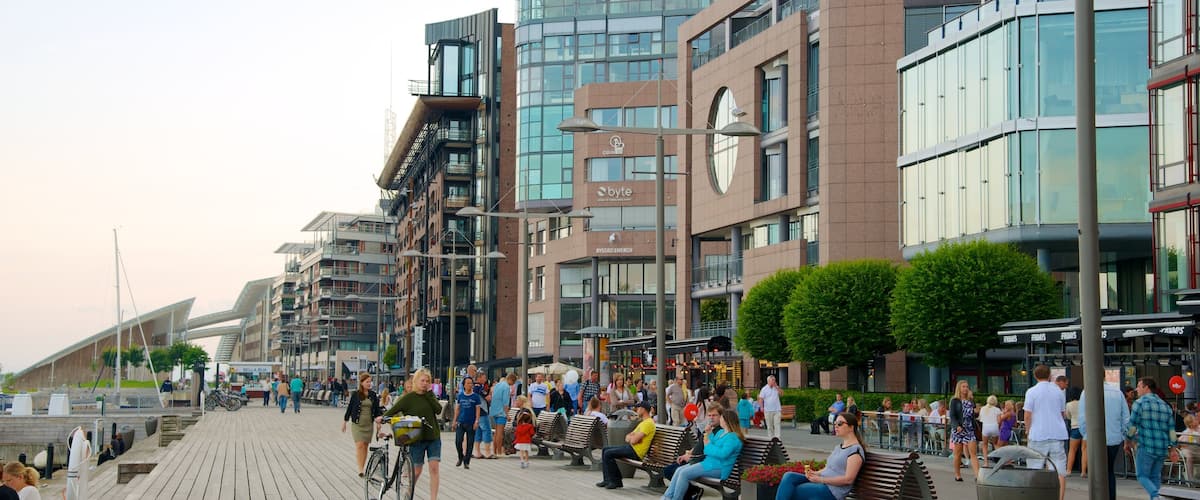 Aker Brygge featuring modern architecture and a coastal town as well as a large group of people