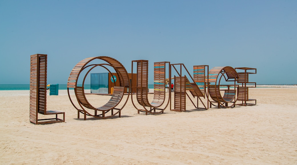 Al Jazaira Beach showing signage, a beach and outdoor art