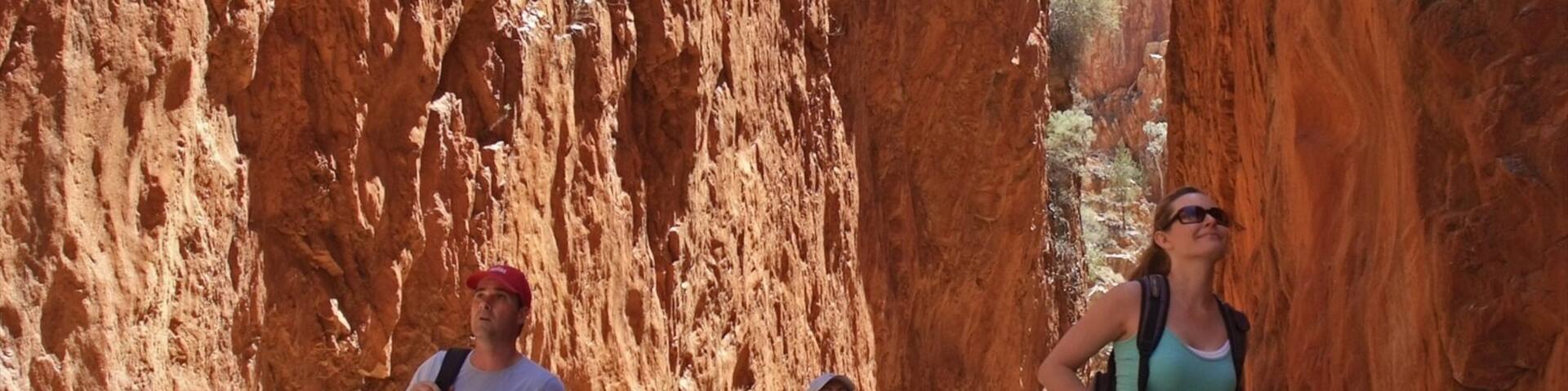 Standley Chasm featuring a gorge or canyon and hiking or walking as well as a small group of people