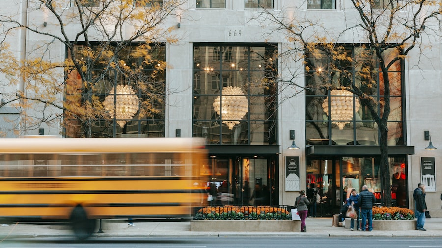 Magnificent Mile shopping on North Michigan Avenue, Chicago, with glass facade, chandeliers, and a passing yellow bus.