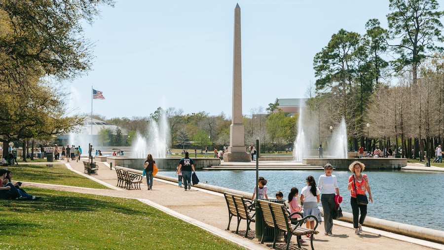 Visitors walking along the reflecting pool and fountains at Hermann Park in Houston, a scenic spot for recreation and relaxation.