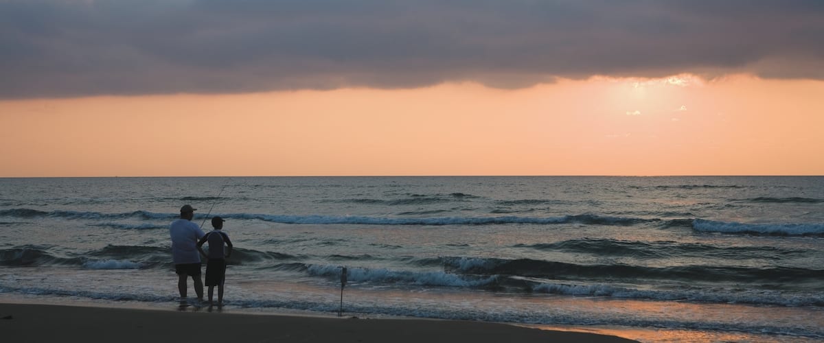 South Padre Island featuring a sandy beach, fishing and a sunset