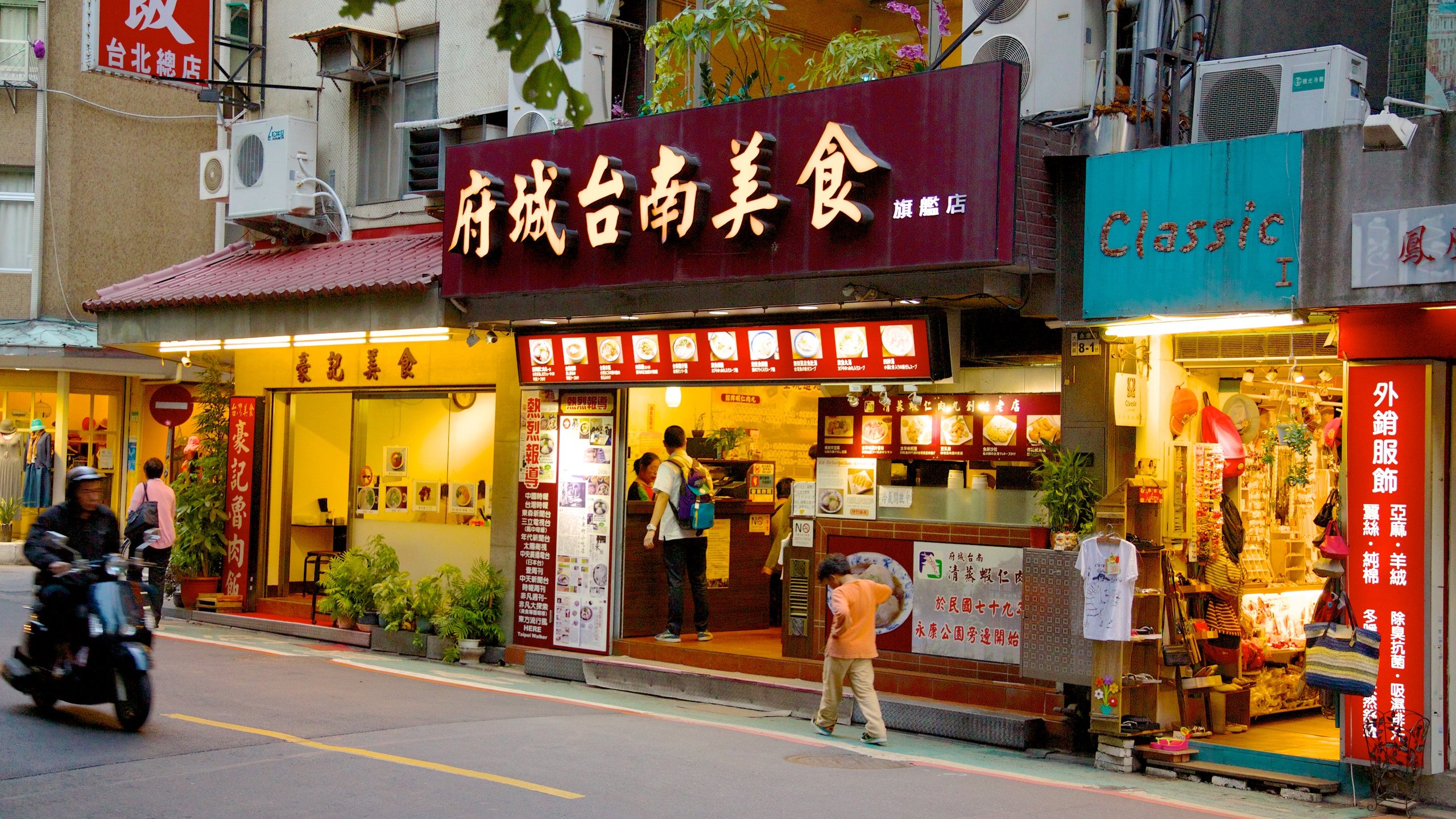 Yong Kang Street showing motorbike riding, shopping and signage