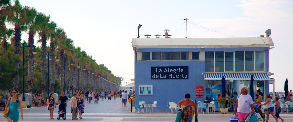 Malvarrosa Beach showing a coastal town and street scenes as well as a large group of people