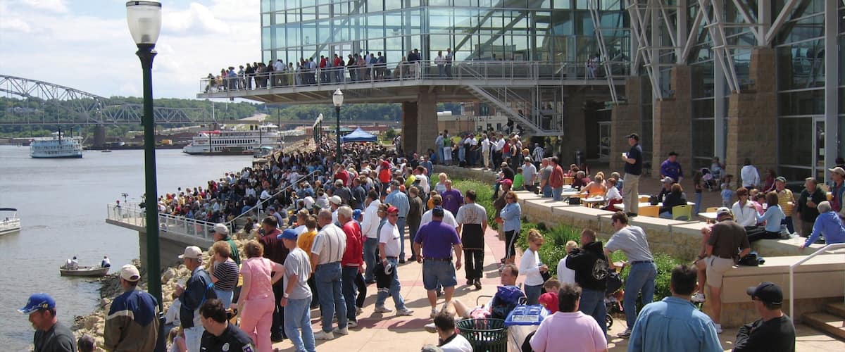 Downtown Dubuque which includes a river or creek and modern architecture as well as a large group of people