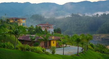 Rocha de Guatapé mostrando uma casa, cenas tranquilas e neblina