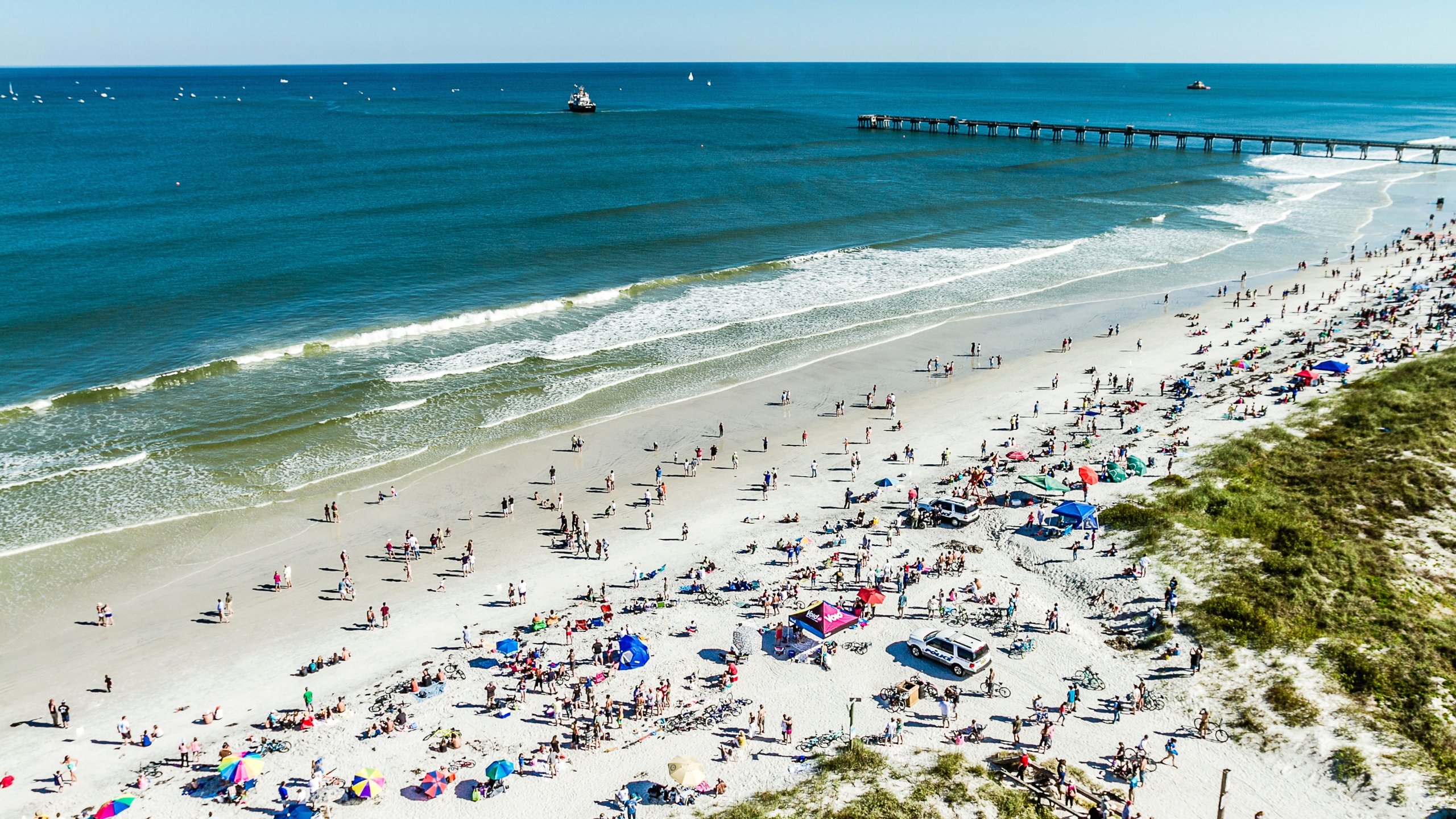 Jacksonville Beach which includes a sandy beach as well as a large group of people