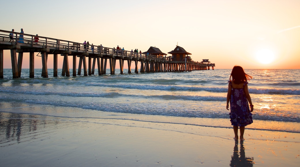 Naples Pier featuring a beach and a sunset as well as an individual child