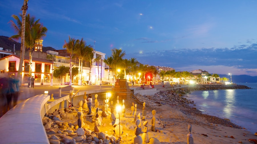 Malecón ofreciendo escenas de noche, una ciudad costera y una playa de arena