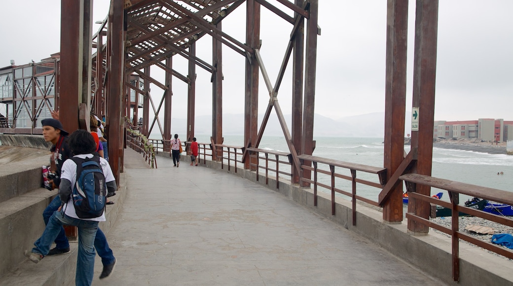 Punta Hermosa que incluye un puente colgante o pasarela y vistas de una costa y también un grupo pequeño de personas