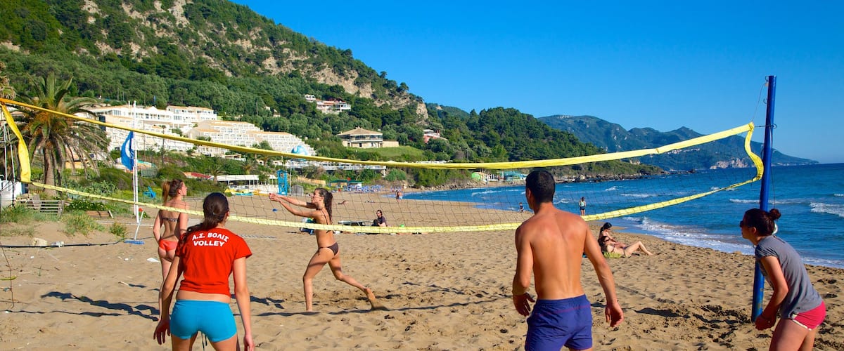 Playa de Pelekas ofreciendo una ciudad costera y una playa de arena y también un pequeño grupo de personas