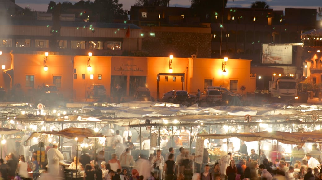 Djemaa el Fna mostrando escenas nocturnas y mercados y también un grupo grande de personas