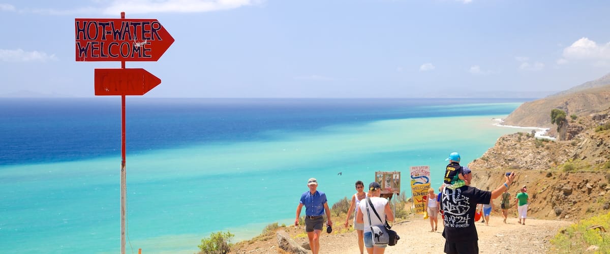 Therma Beach which includes general coastal views, signage and hiking or walking