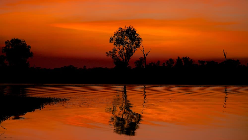 Kakadu National Park which includes a lake or waterhole and a sunset