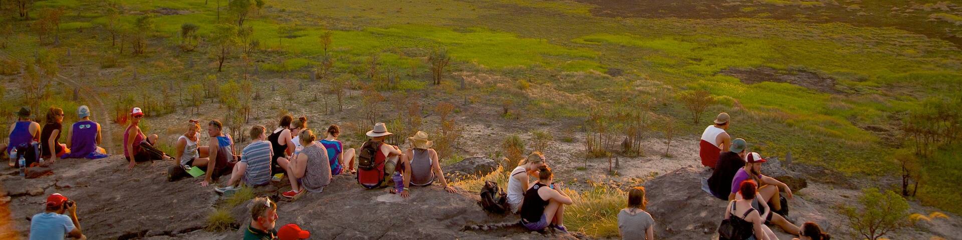 Ubirr featuring a sunset as well as a large group of people