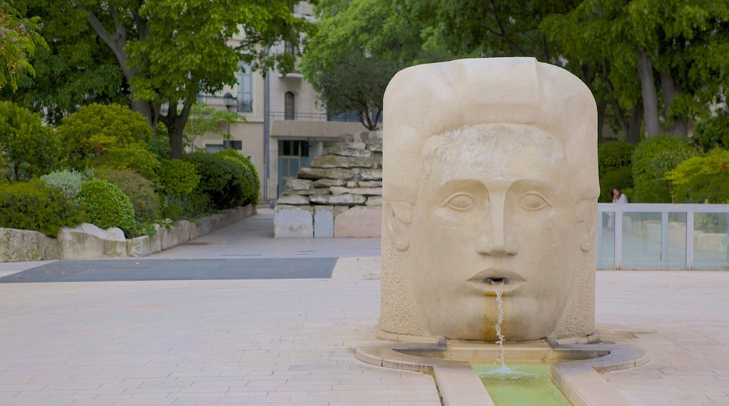 Nimes som visar en fontän, en staty eller skulptur och gatuliv