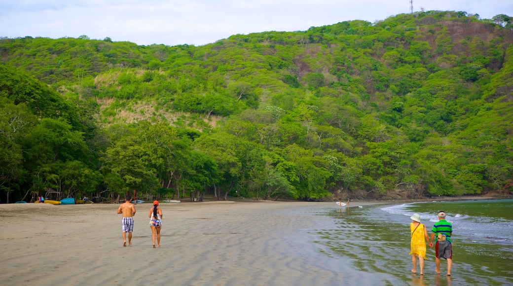 Playa de Bahía Hermosa mostrando una playa de arena y montañas y también un pequeño grupo de personas