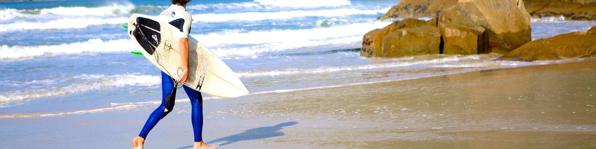 Matadeiro Beach showing surfing and a sandy beach as well as an individual male
