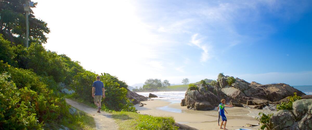 Matadeiro Beach which includes rocky coastline and a sandy beach as well as a small group of people