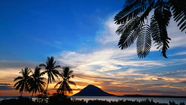 Manado which includes general coastal views, mountains and a sunset