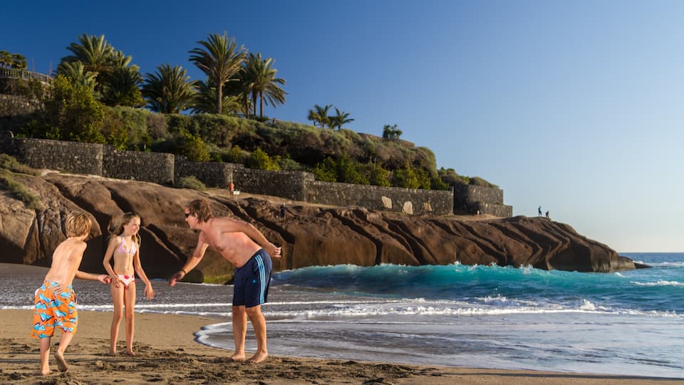 Adeje showing a sandy beach and swimming as well as a family