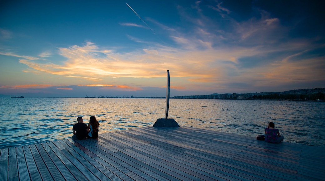 Tesalónica que incluye vistas de una costa y un atardecer y también un grupo pequeño de personas