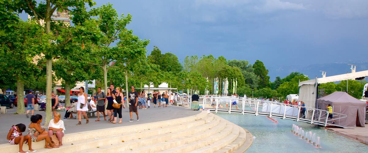 Lausanne featuring a square or plaza and a pond as well as a large group of people